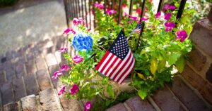 Small American flags in a flower planter on the brick front steps of a home