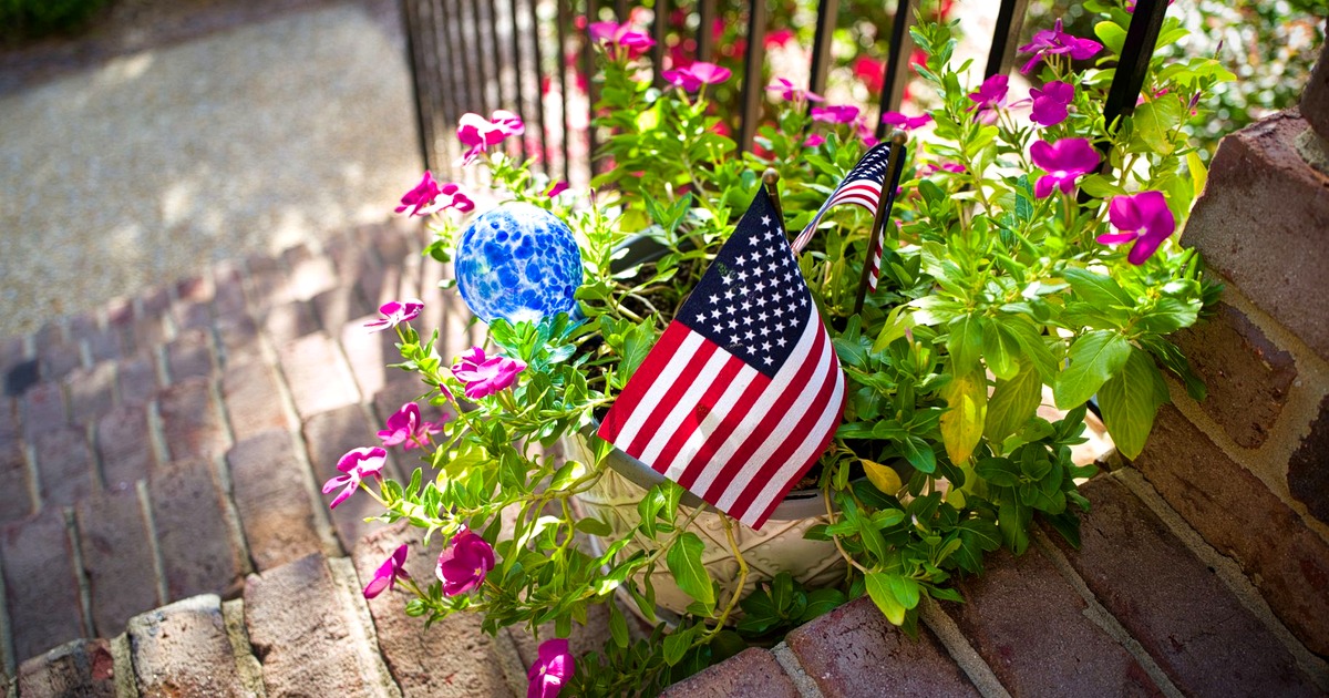 Small American flags in a flower planter on the brick front steps of a home