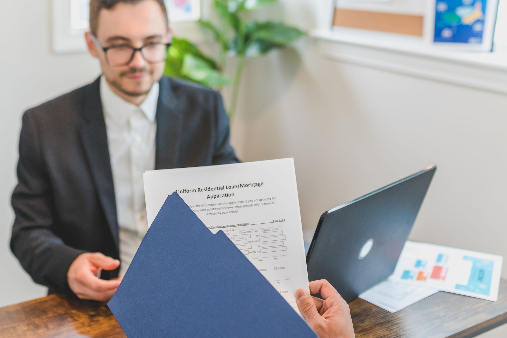 A loan officer and a homebuyer reviewing mortgage loan documents across a table.