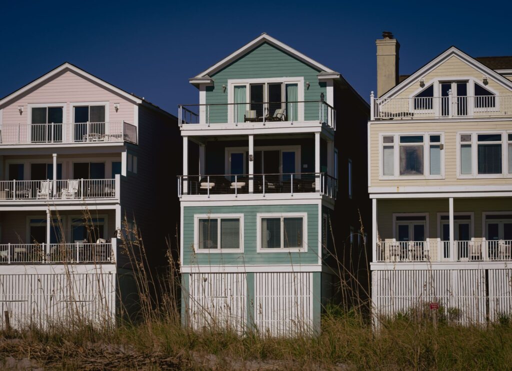 A row of coastal homes with wooden siding under a clear sky.
