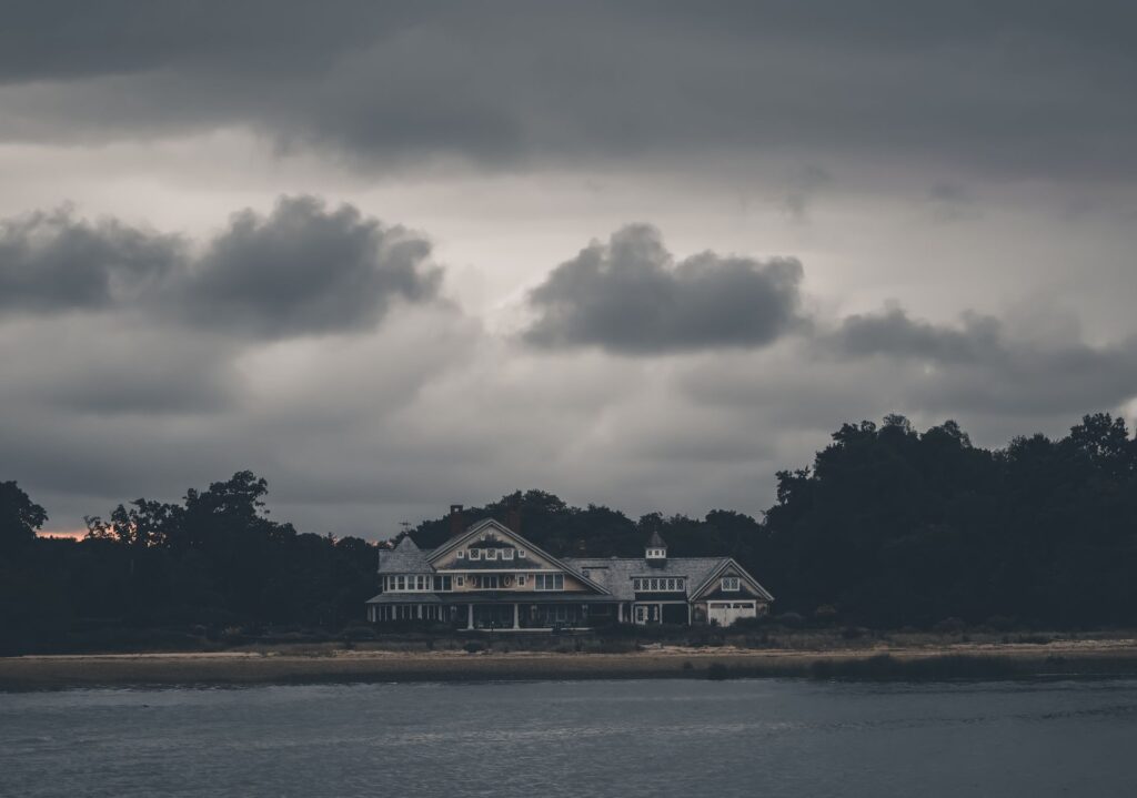 A single house on the coast under heavy storm clouds.