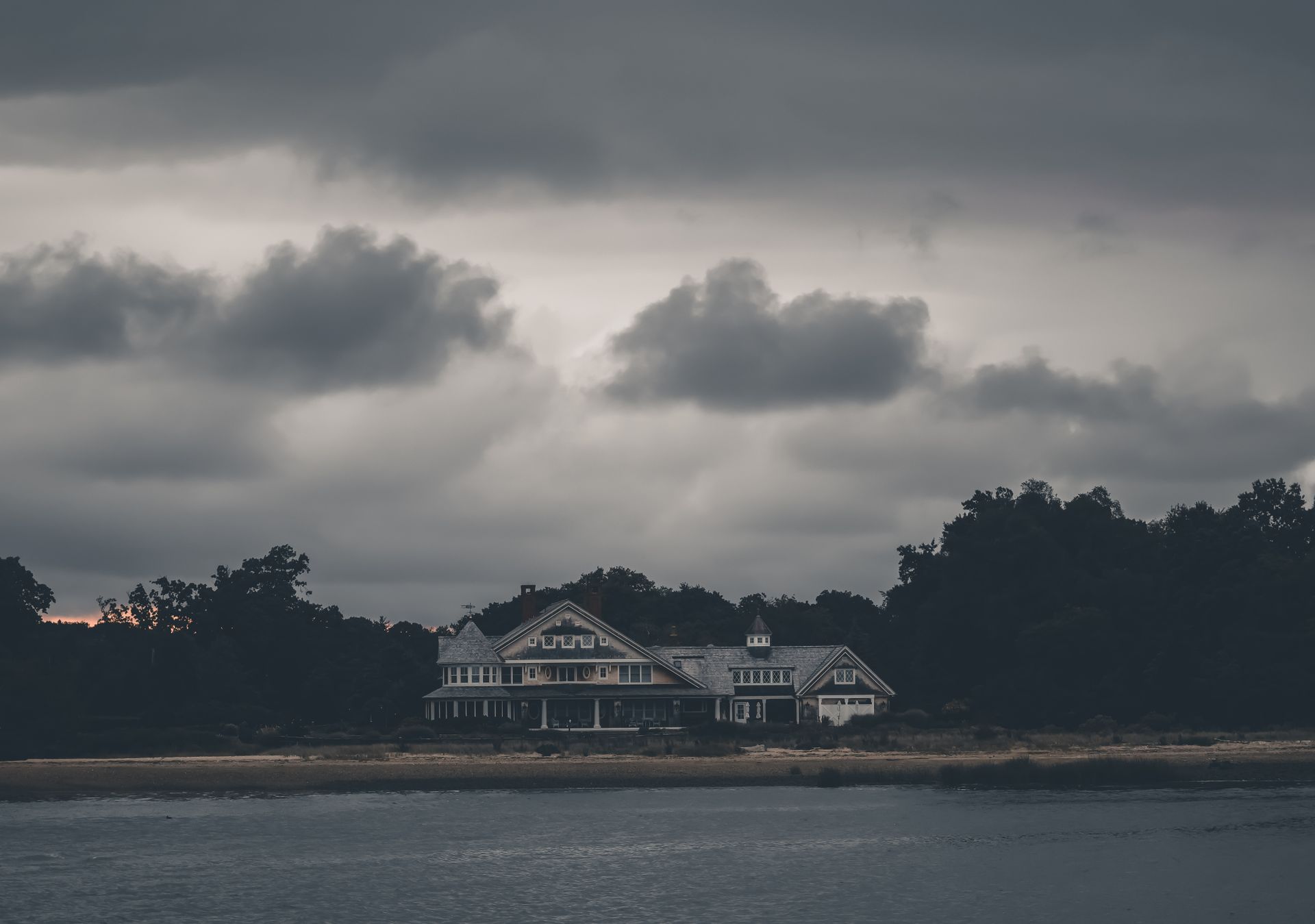 A single house on the coast under heavy storm clouds.