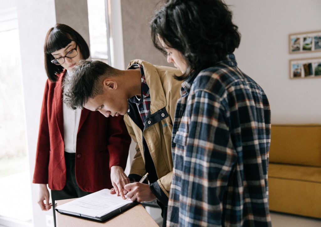 A couple signing real estate disclosure paperwork with their agent at a table