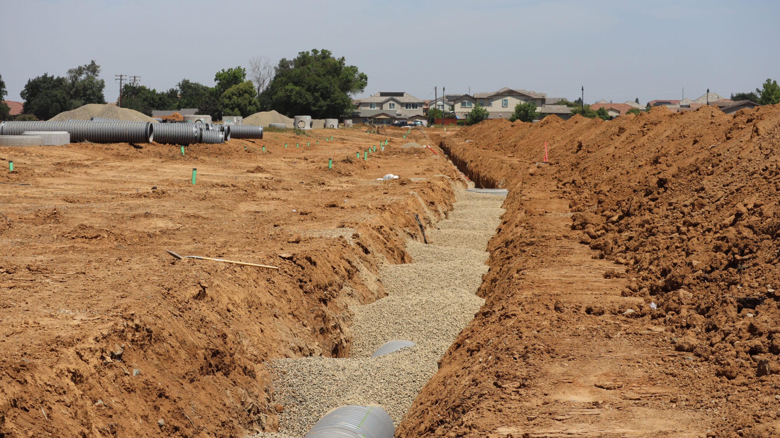 Excavated utility trench with large pipes during underground septic or sewer line installation in a suburban Wilmington, NC-area neighborhood