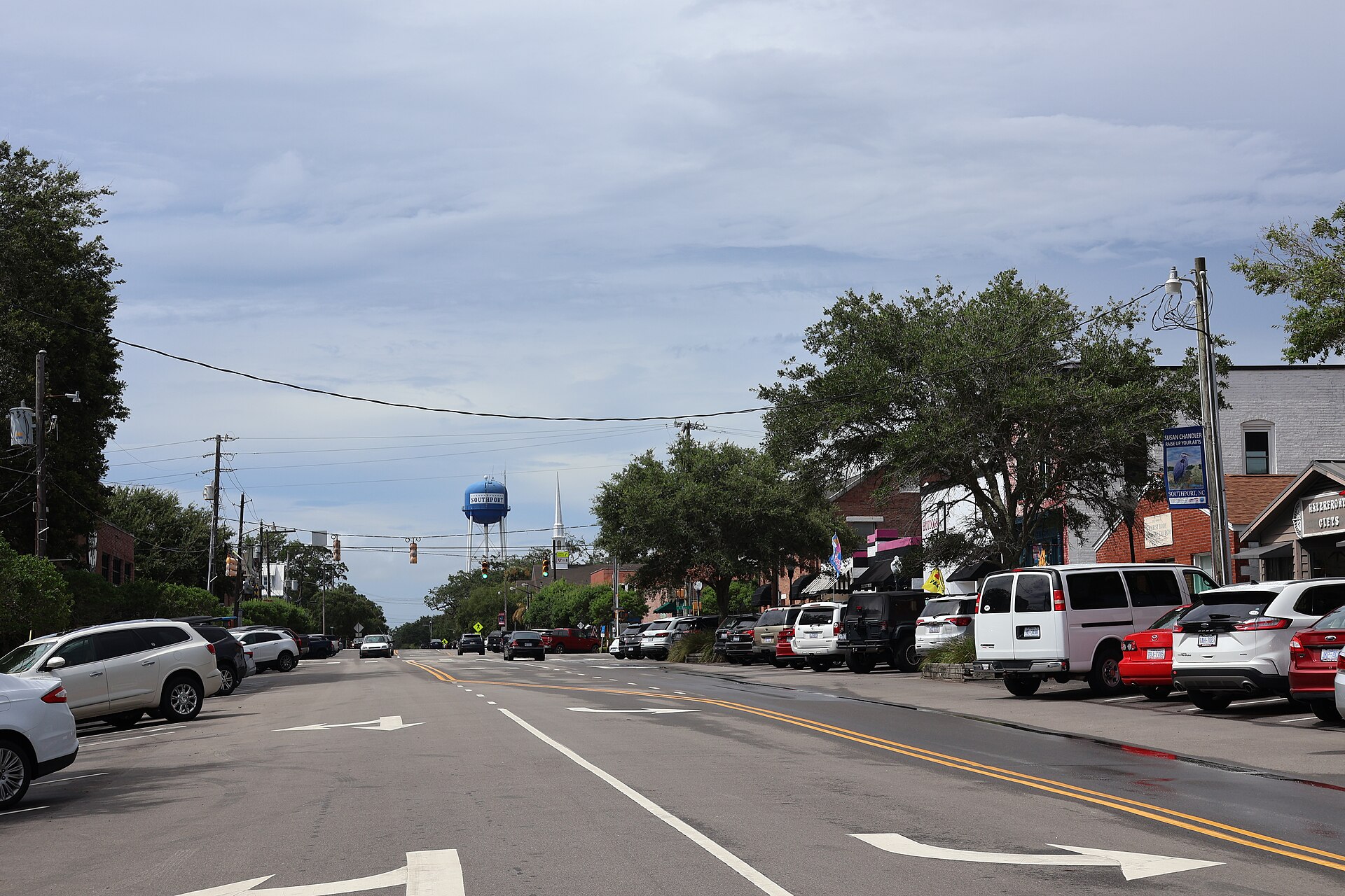 South Howe Street in downtown Southport, North Carolina, with shops, parked cars and the Southport water tower in the distance