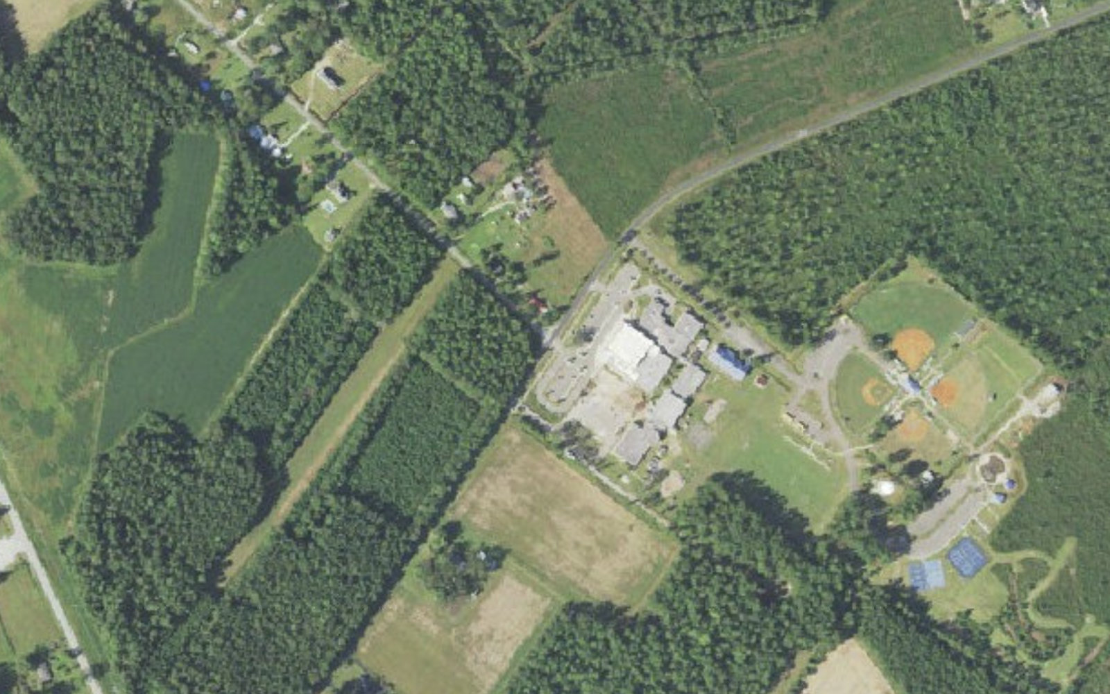 Aerial view of Waccamaw School and the ball fields, tennis courts and playground of Waccamaw Park on Waccamaw School Road NW in Ash, North Carolina, surrounded by farm fields and planted pine