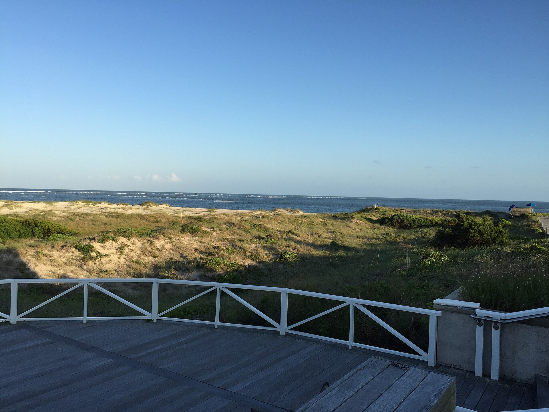 View from a beach house deck at Shoals Point on Bald Head Island, North Carolina, over vegetated dunes to the breaking shoals and the Atlantic Ocean beyond