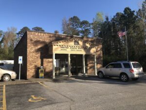 United States Post Office building for Bolivia, North Carolina 28422, with flag and parking lot