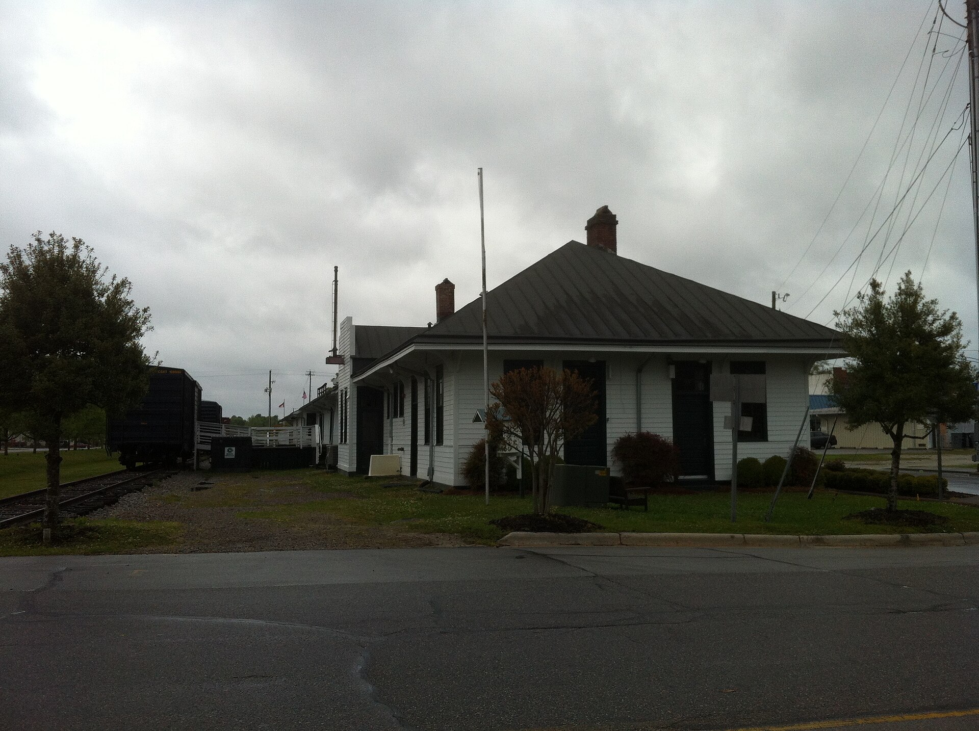 The historic Burgaw train depot, a white frame railroad station with a boxcar on the siding beside it, in Burgaw, North Carolina