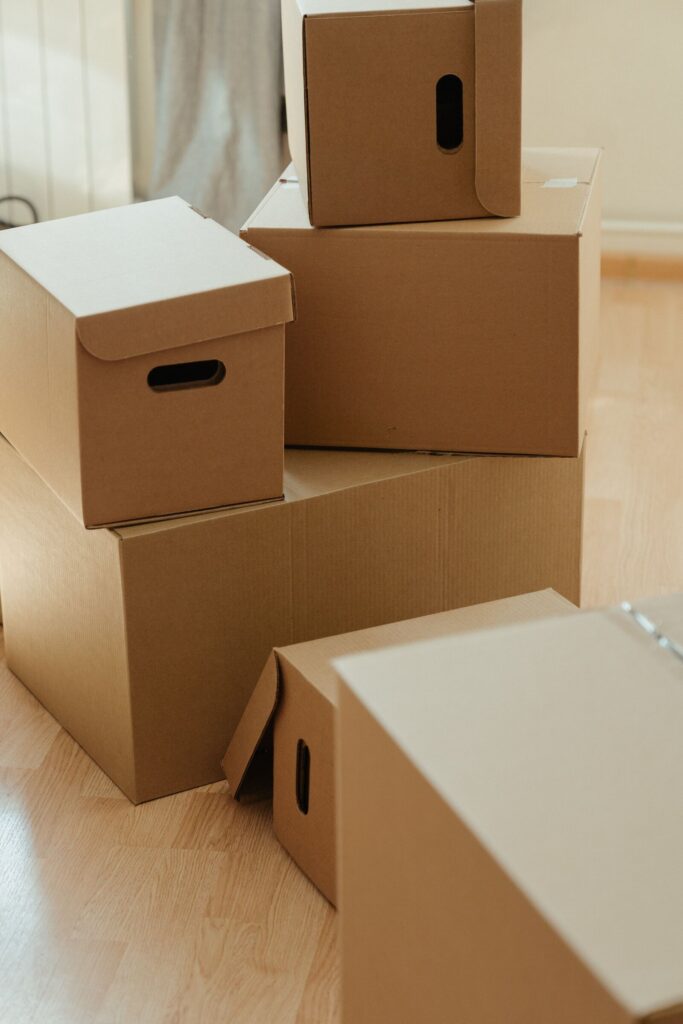 Cardboard moving boxes stacked on a wood floor in an empty room