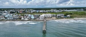 Aerial view of Carolina Beach, North Carolina, showing oceanfront homes, the fishing pier and the marsh behind the island.