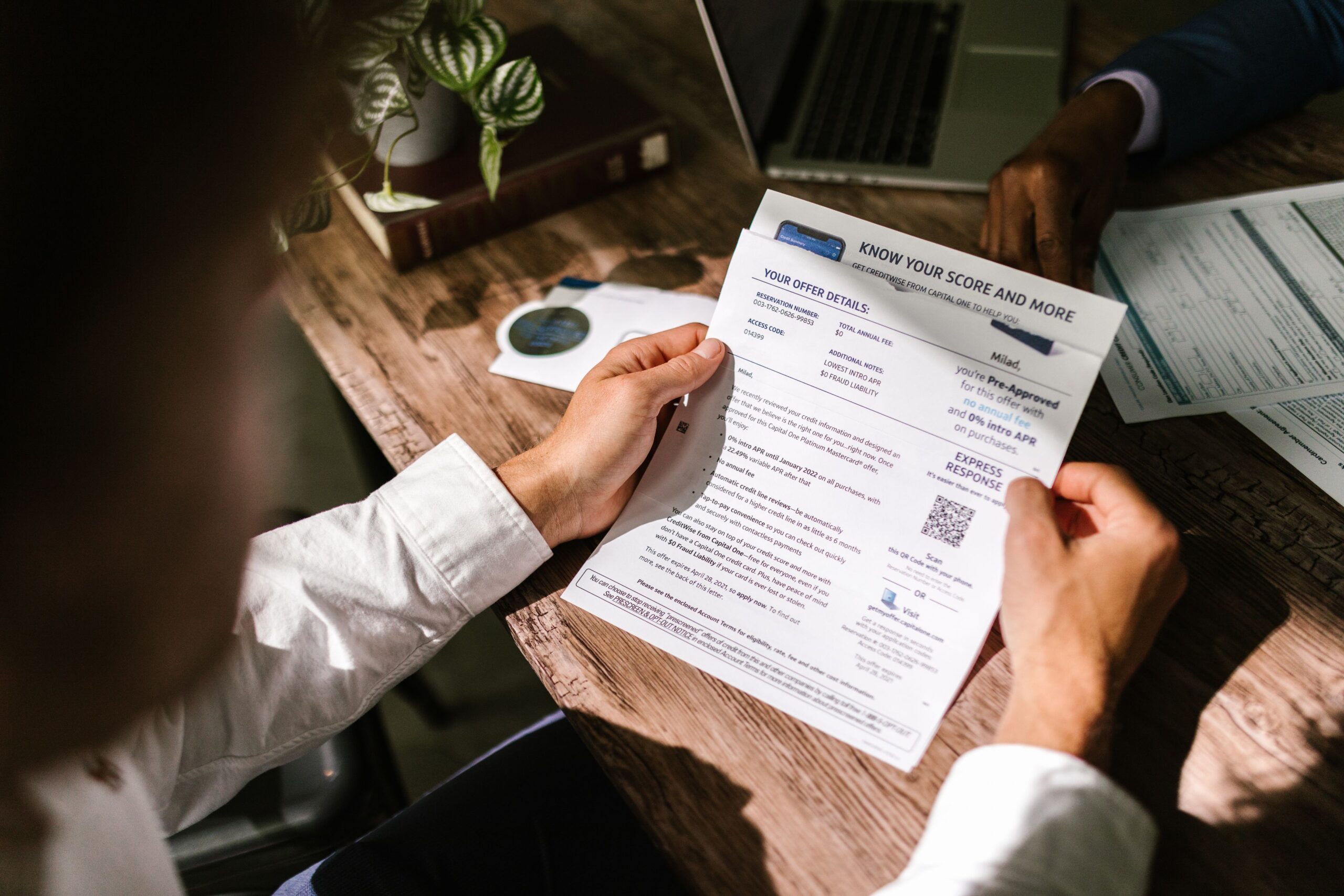 A man reviewing a financial document at a wooden desk in natural light