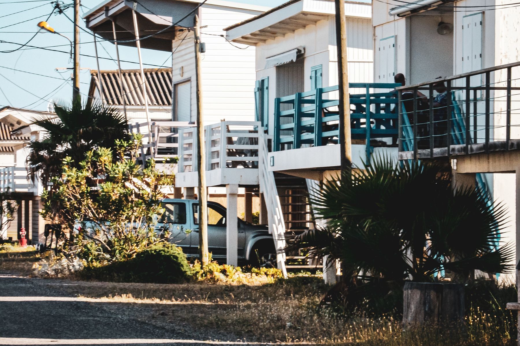A row of coastal cottages raised on pilings with open parking and stairs underneath the elevated living level