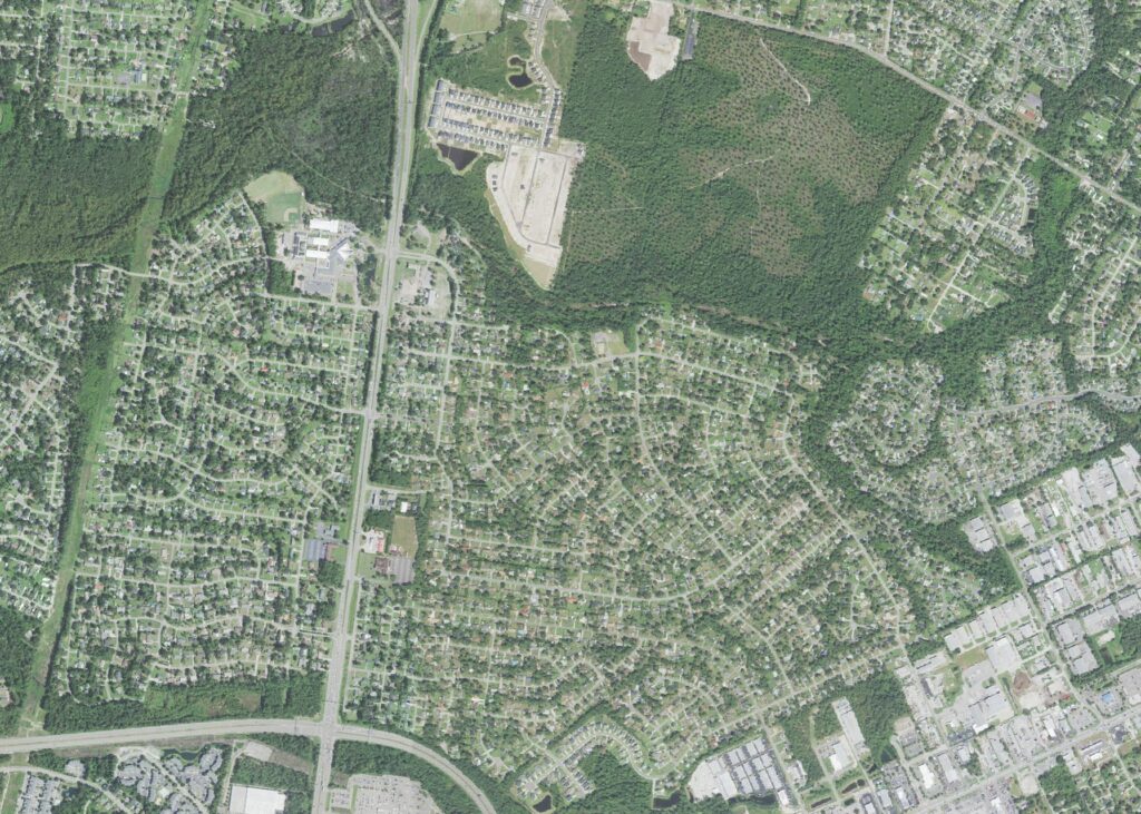 Aerial view of the King's Grant neighborhood in Wilmington, North Carolina, showing its curving 1970s street grid under heavy tree canopy, a school campus with ball fields, North College Road running north to south, and the Market Street commercial corridor at lower right