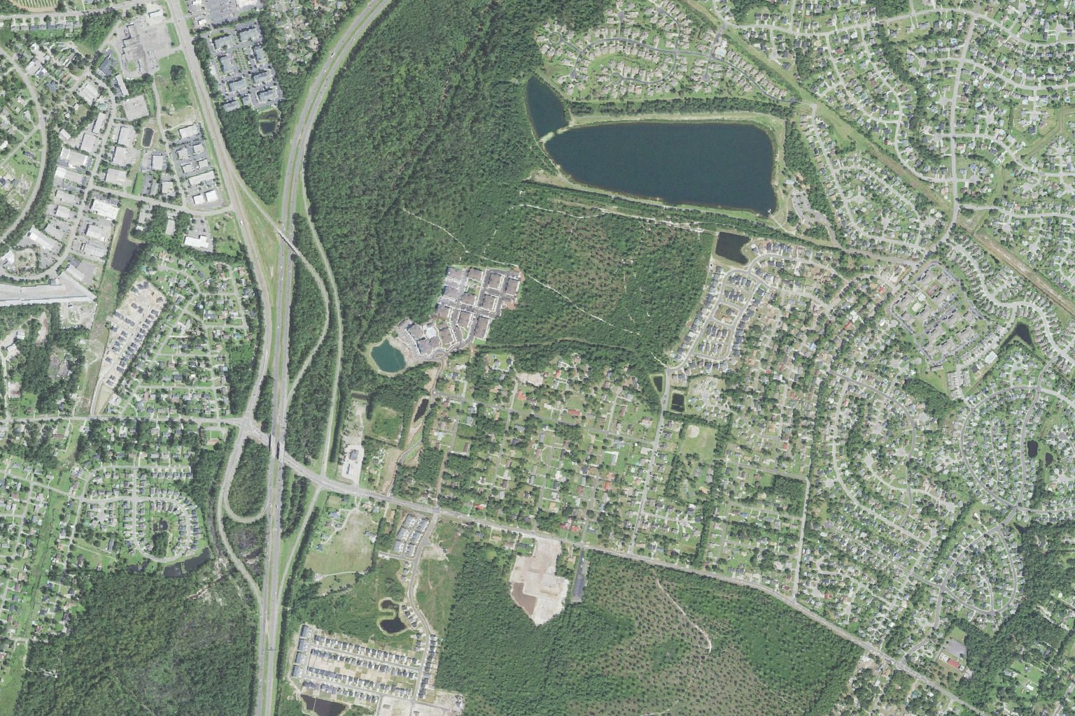 Aerial view of the northern edge of King's Grant in Wilmington, North Carolina, showing the thirty-five acre lake at Smith Creek Park, the Gordon Road corridor, and the Interstate 40 interchange at left