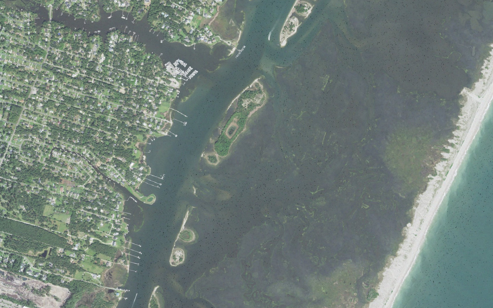 Aerial view of the south end of Masonboro, Wilmington, North Carolina, showing the marina at the end of Trails End Road, private docks along Masonboro Sound, the Intracoastal Waterway channel, and the marsh and ocean beach of Masonboro Island Reserve