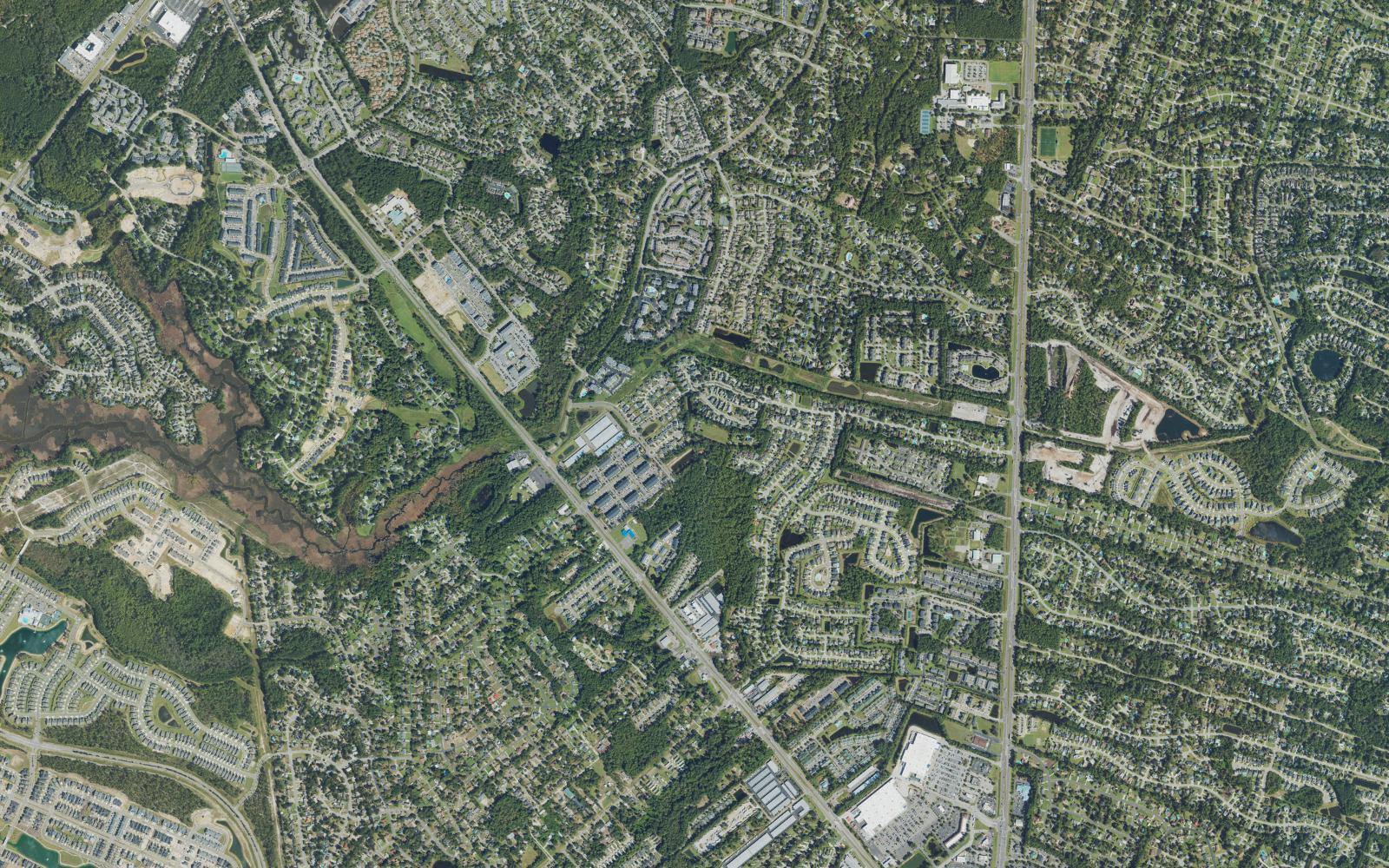 Aerial overview of the Monkey Junction area of Wilmington, North Carolina, with Carolina Beach Road running diagonally and South College Road down the right, a wooded creek marsh at the left edge, and the junction and its shopping centers at lower right