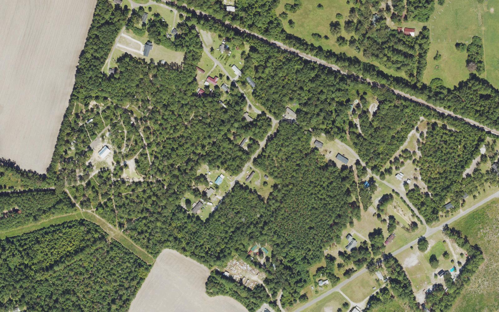 Aerial view of wooded acreage, scattered homes and a farm field along Smith-Briggs Lane in Northwest, Brunswick County, North Carolina