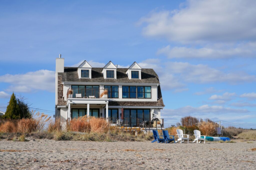 An elevated oceanfront home with Adirondack chairs and sea oats on a clear winter day