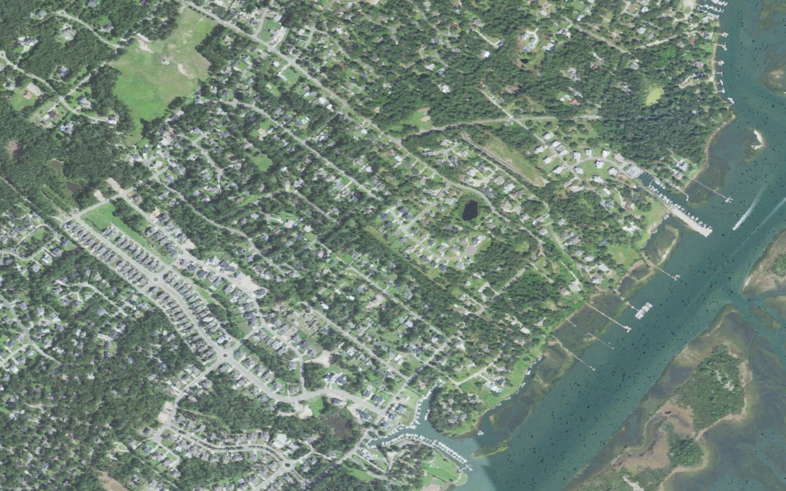 Aerial view of the Middle Sound side of Ogden, North Carolina, showing wooded neighborhoods, private docks on tidal creeks, marsh and the Intracoastal Waterway