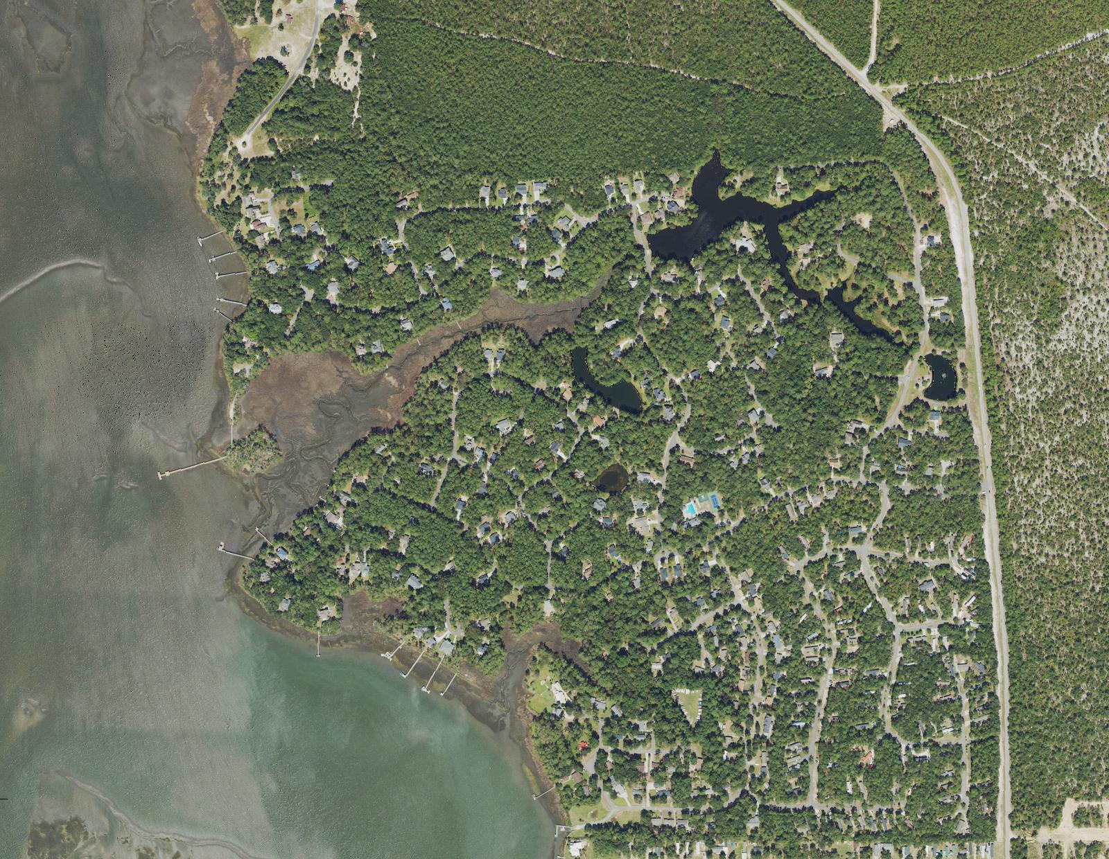 Aerial view of River Run Plantation in Bolivia, North Carolina, showing wooded homesites, interior ponds, the community amenity center and private docks along the Lockwood Folly River