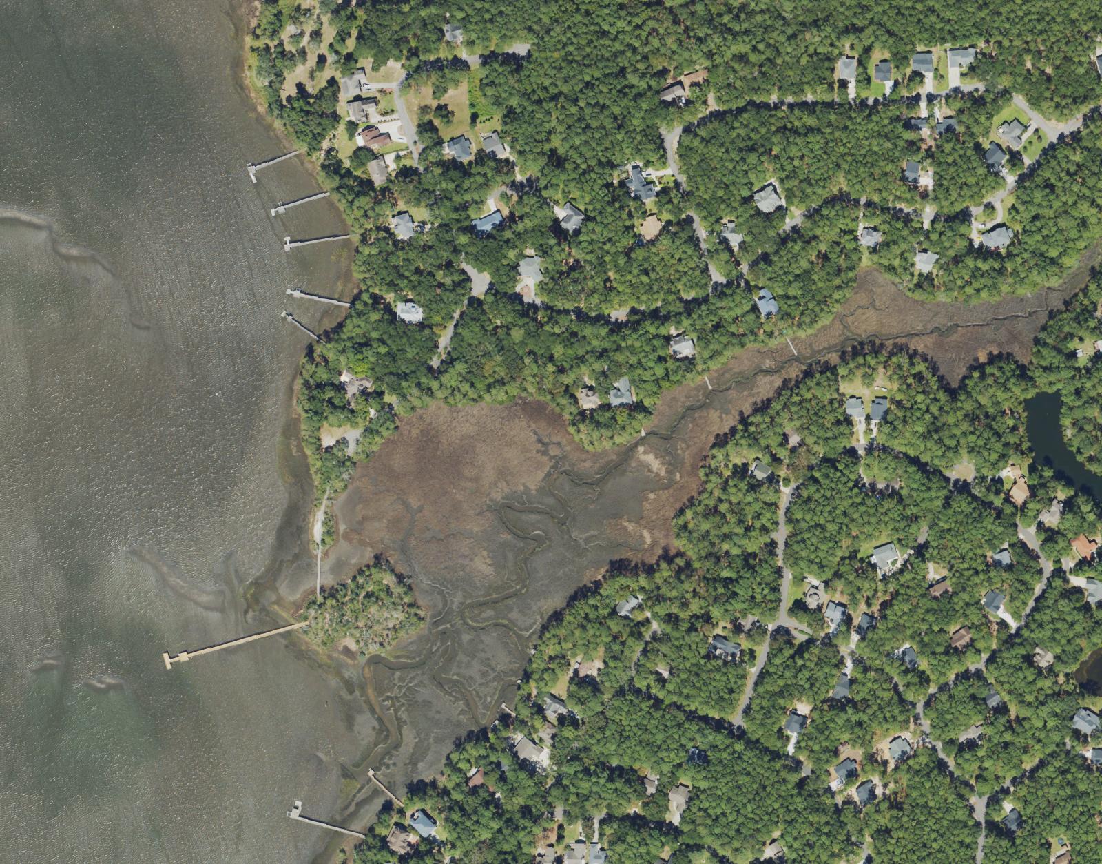 Aerial view of the Lockwood Folly River shoreline at River Run Plantation, with private docks, salt marsh creeks and the long community pier reaching out over the marsh to open water