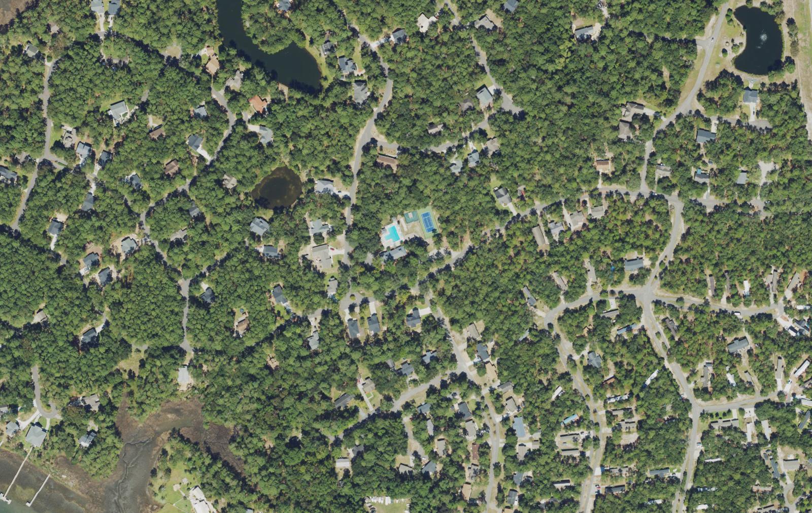 Aerial view of the River Run Plantation amenity center in Bolivia, North Carolina, showing the community pool, tennis and pickleball courts, clubhouse and two catch-and-release ponds among wooded lots