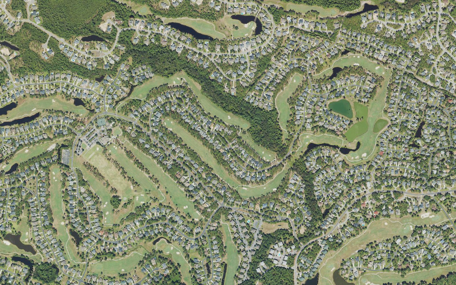 Aerial view of the golf core of St. James Plantation, North Carolina, with fairways, lagoons, wooded buffers and cul-de-sac streets of single family homes