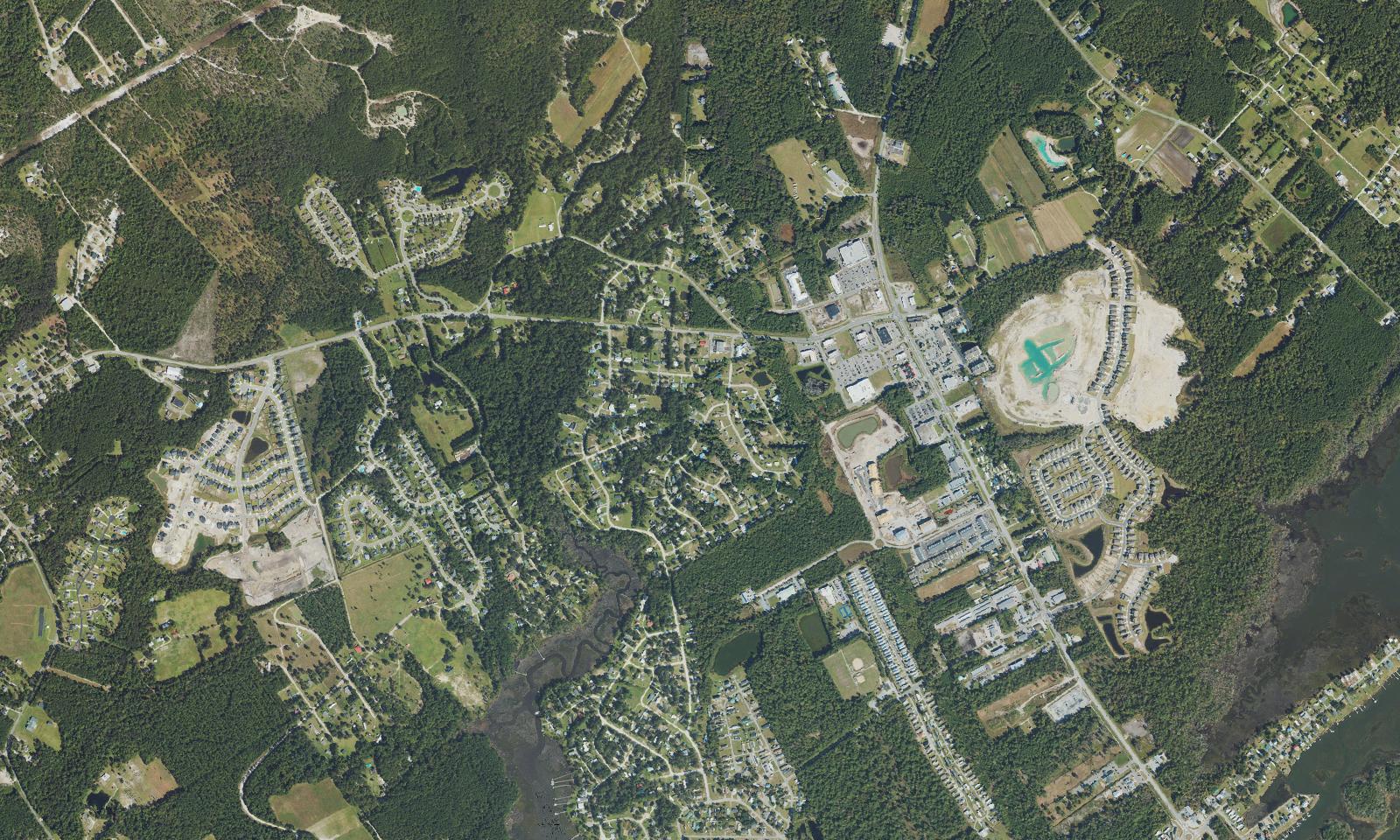 Aerial view of the mainland side of Surf City, North Carolina, west of the Intracoastal Waterway, showing newer subdivisions, shopping and commercial development along the N.C. 50 and N.C. 210 corridor and the wooded land still being cleared