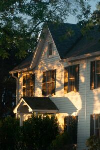 Classic white two-story home with dark shutters in warm golden-hour light