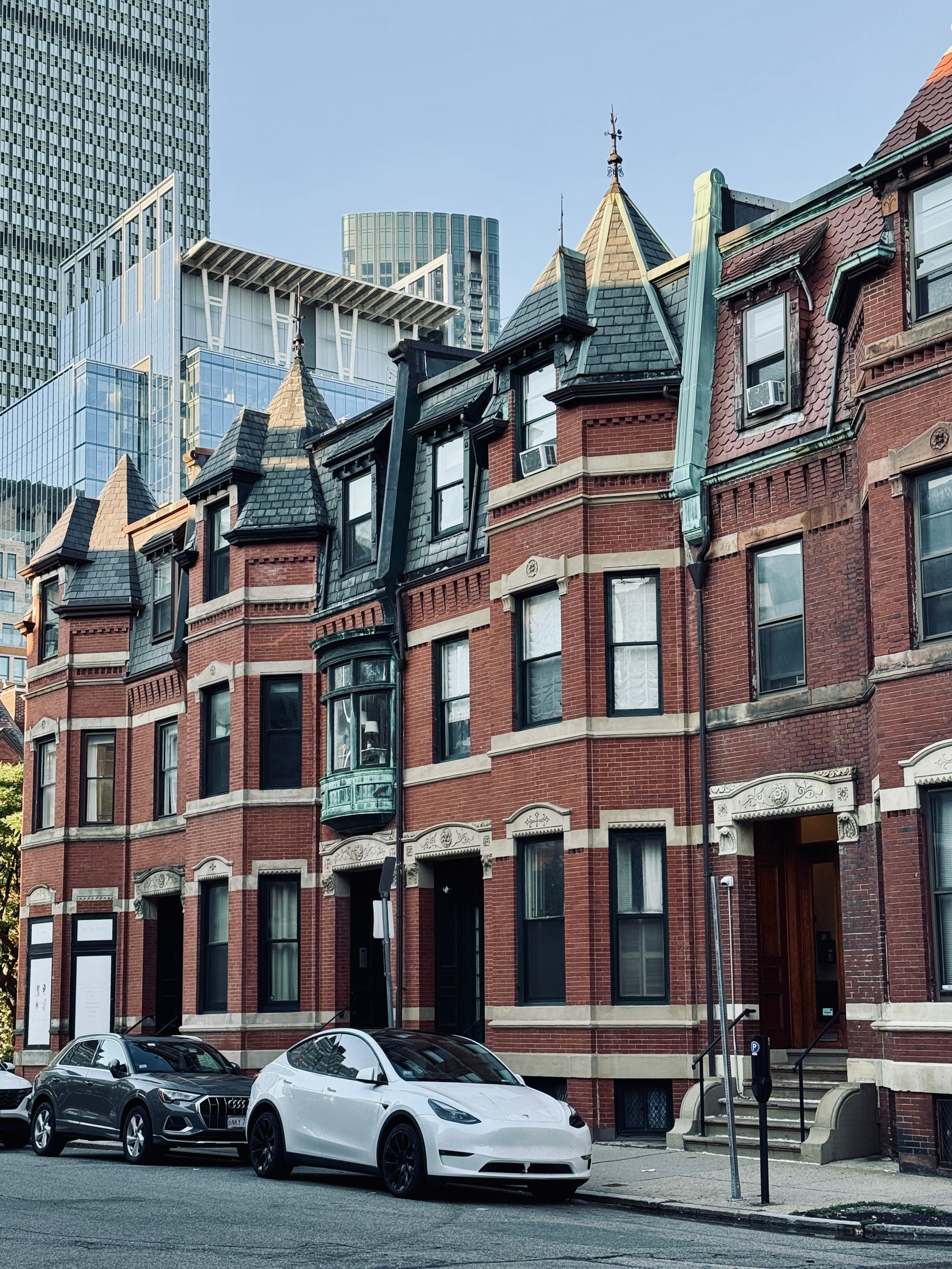 Red brick row houses on a historic Boston street with downtown towers behind them