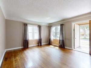 An empty living room with hardwood floors in a house listed for sale