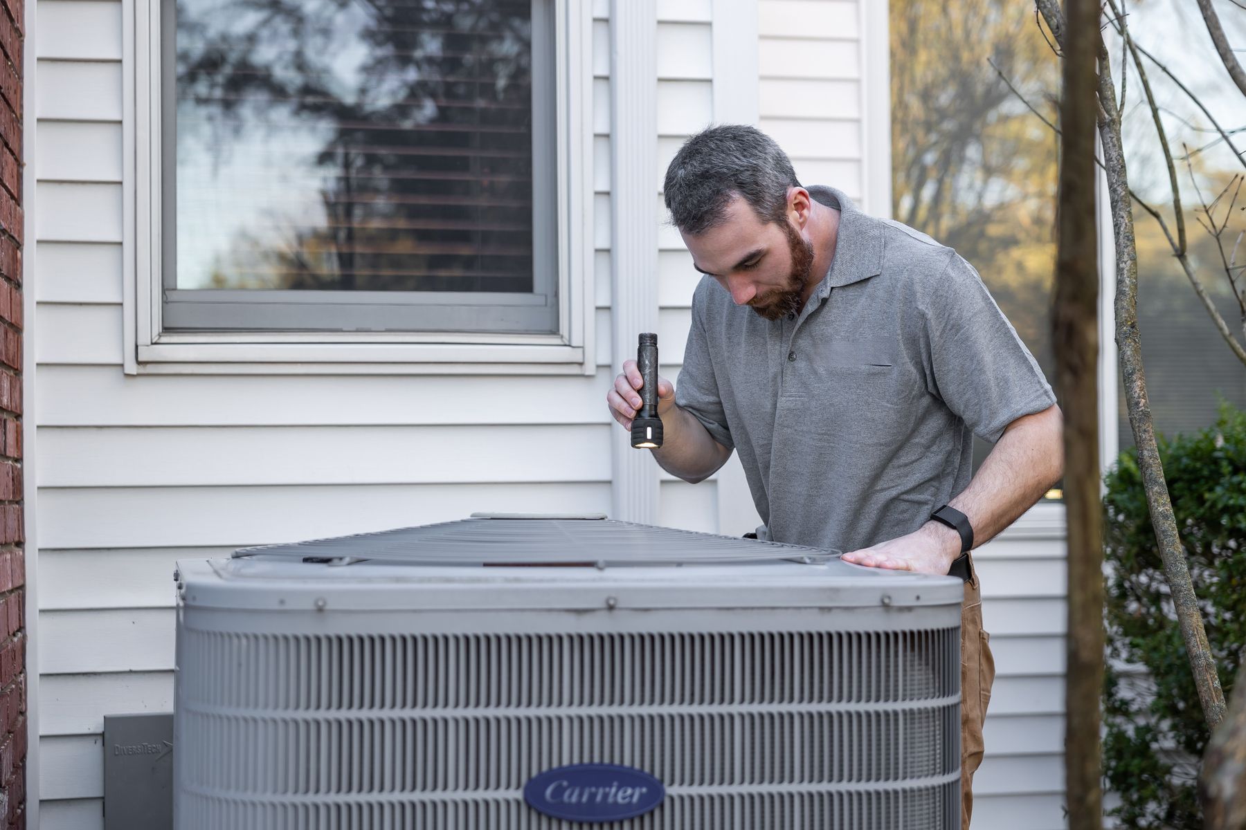 Technician checking the outdoor condenser unit of a residential heat pump system
