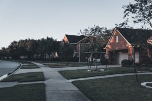 An established suburban street of brick homes with mature trees at dusk