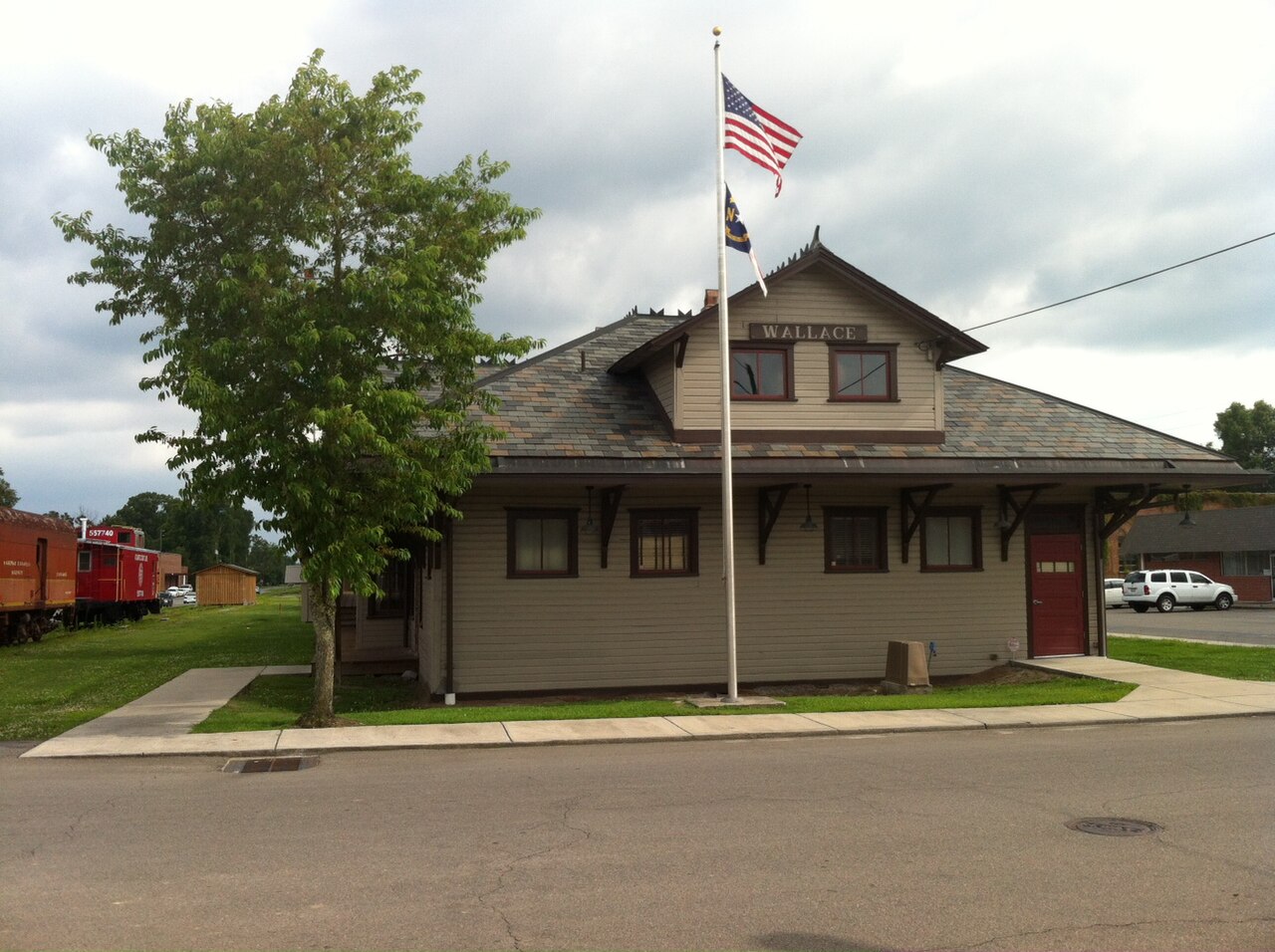 Restored Wallace railroad depot with a red caboose and flagpole in Wallace, North Carolina
