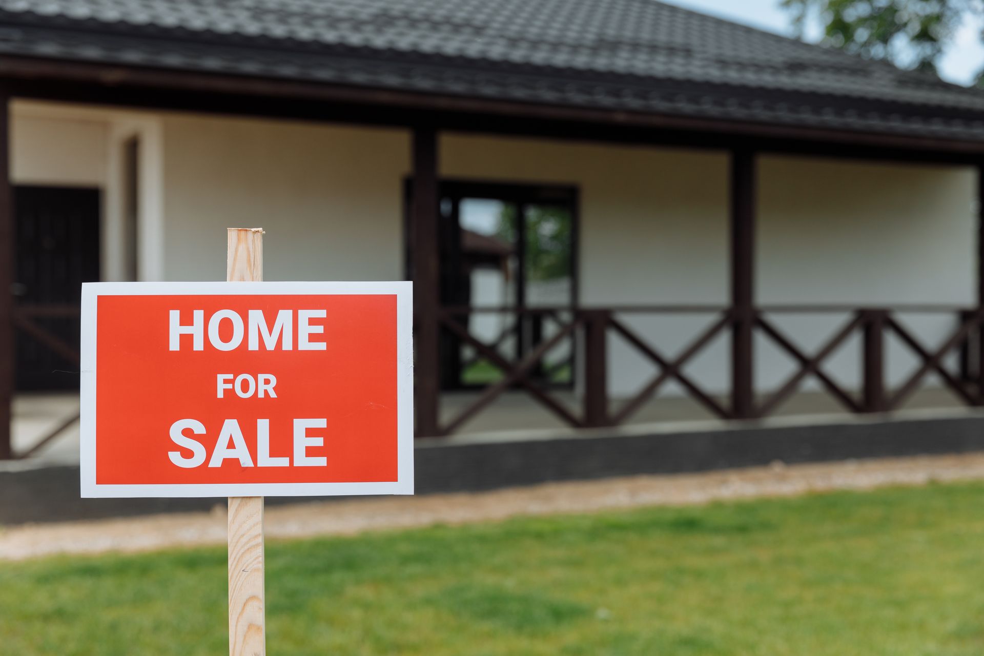 Home for sale sign in front of a house with a covered porch