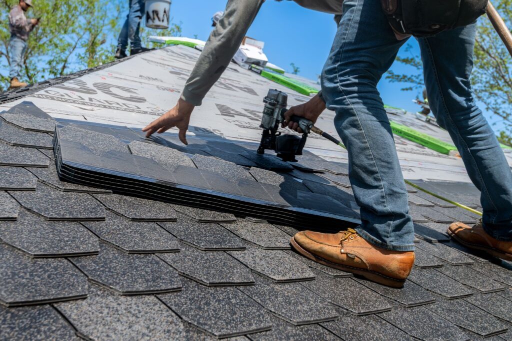 A roofer installing asphalt shingles on a new roof