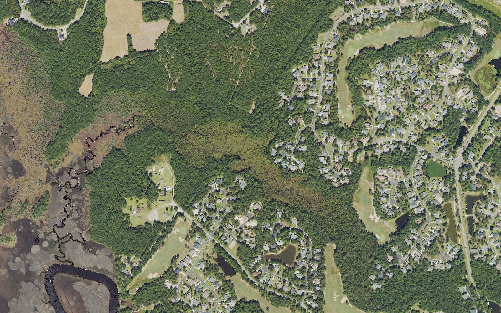 Aerial view of the western edge of Winding River Plantation, where homesites and fairways give way to woods, then to the salt marsh and tidal creeks of the Lockwood Folly River